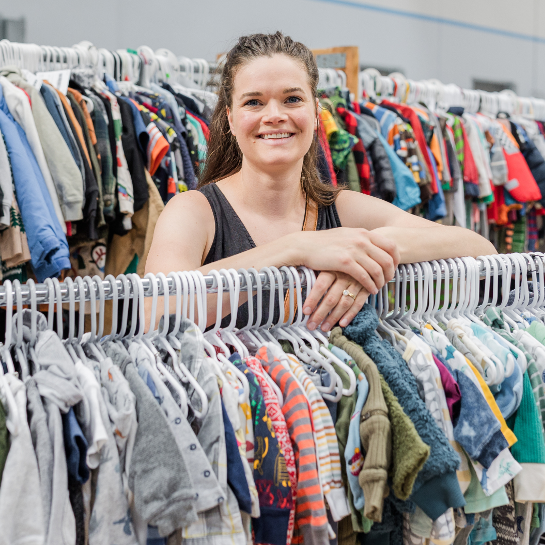 A mom stands in front of her clothing she is selling at the JBF Sale